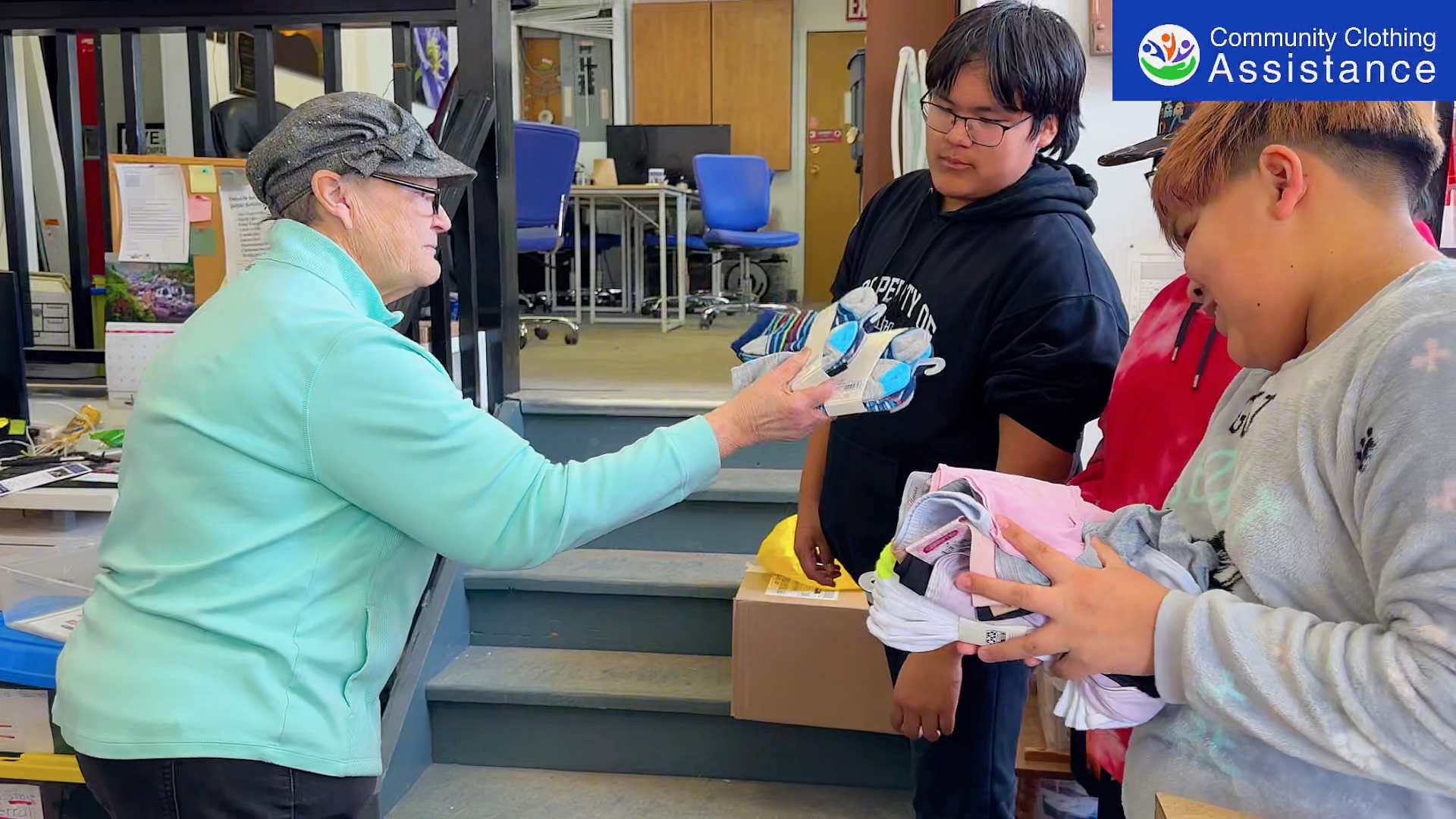 A Community Clothing Assistance volunteer handing new socks to young people through the Undercover Project